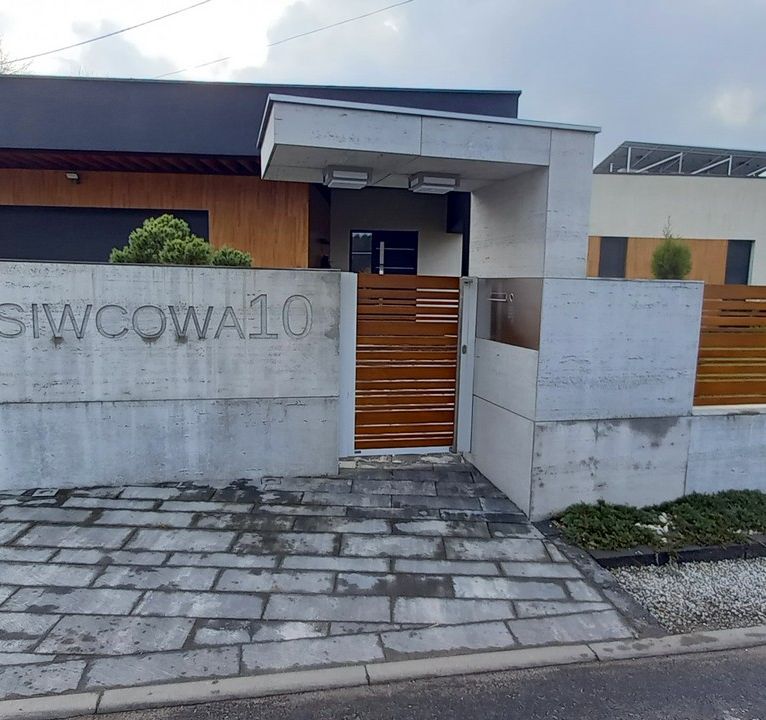 Nowoczesny front ogrodzenia wykonanego z aluminium drewnopodobnego, montowanego do murów z betonu architektonicznego- realizacja Tarnowskie Góry.