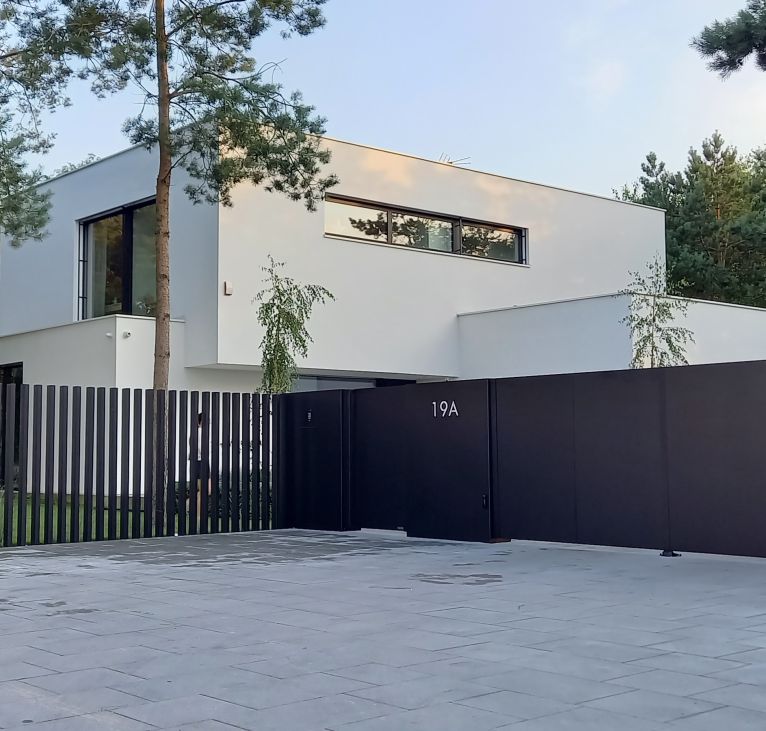 Nowoczesne ogrodzenie aluminiowe z pełną bramą i furtką oraz pionowymi przęsłami na tle nowoczesnej bryły budynki - realizacja Mazowieckie, Warszawa